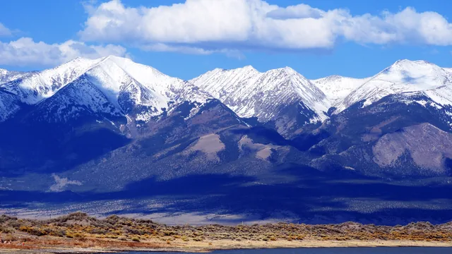 Snow-capped mountains rising above a dry valley in Colorado.