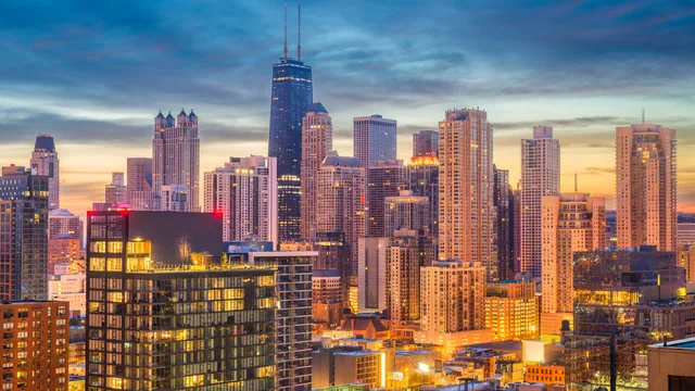 Chicago skyline at sunset with tall buildings in warm light.