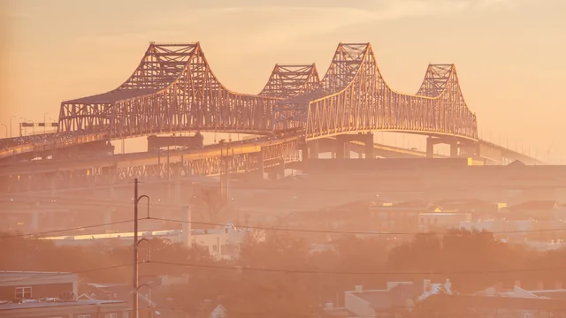 A large steel truss bridge in an orange haze in Louisiana.