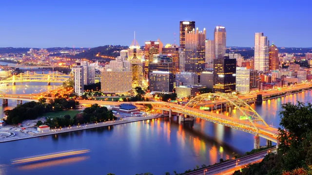 A city skyline and bridges over a river at dusk in Pennsylvania.