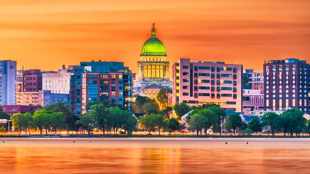 A domed capitol building and city skyline across the water at sunset in Wisconsin.
