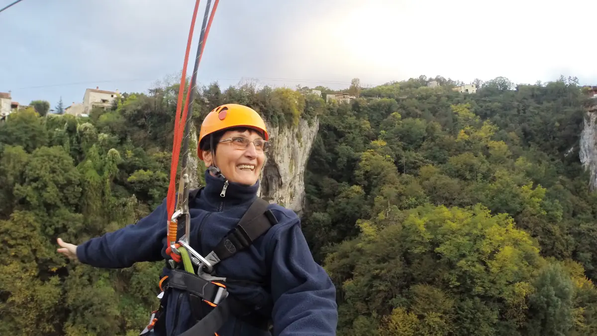 An older woman riding a zip line on vacation